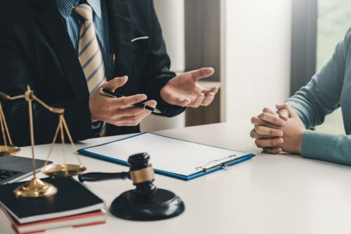 lawyer and client sitting at table with gavel and scales of justice - referring client to an appeals attorney concept